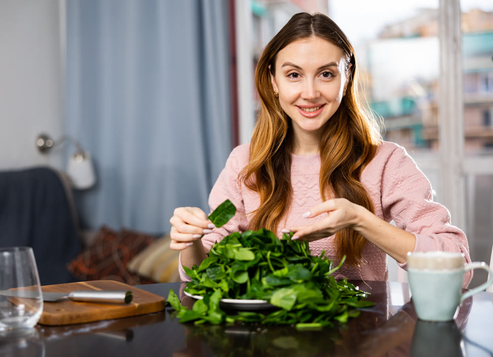 Young woman sorts fresh spinach