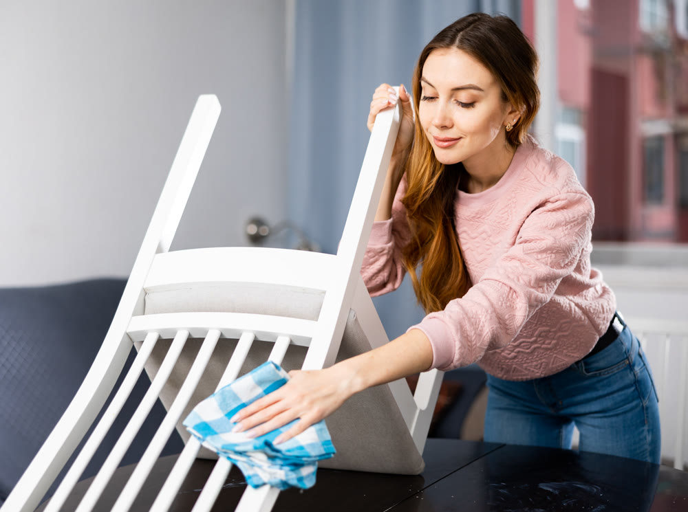 Young woman wipes a chair with a damp cloth