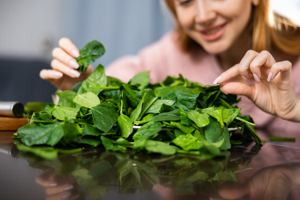 Girl carefully examines spinach leaves for salad