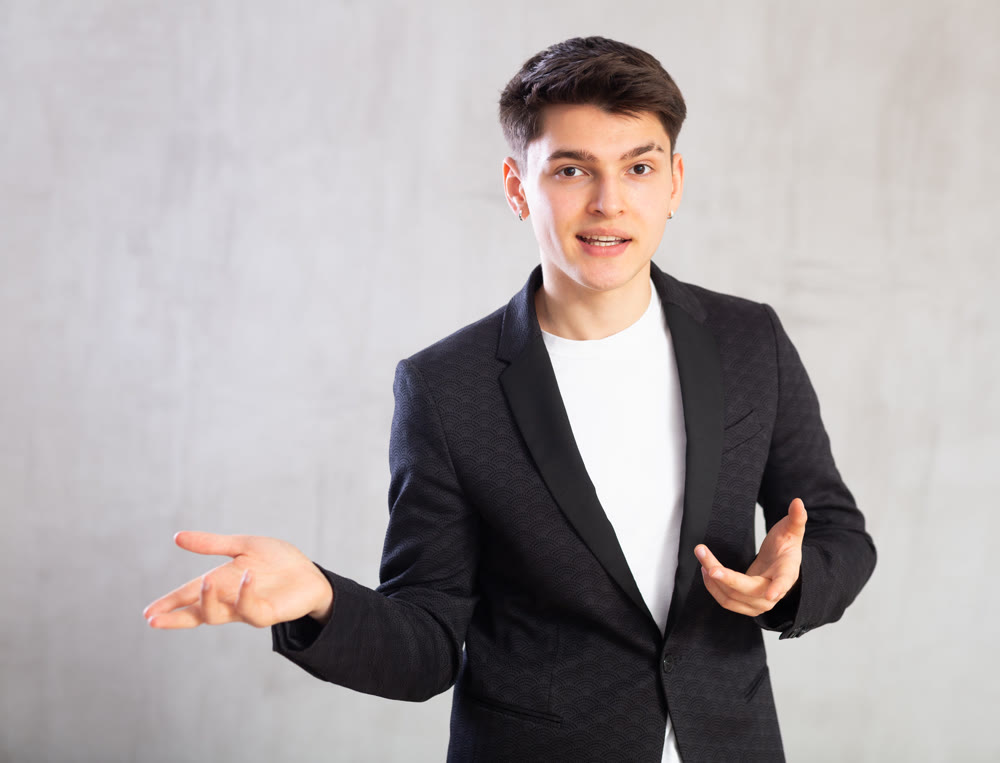 Smiling surprised young male student in suit jacket pointing at you.Portrait of guy pointing finger