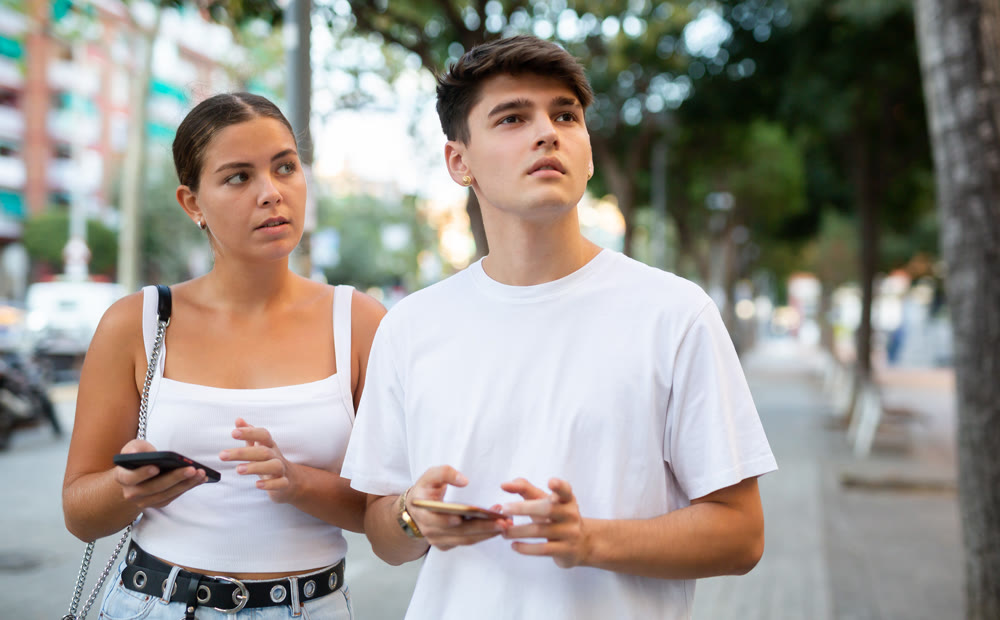 Modern man and woman strolling together and phubbing