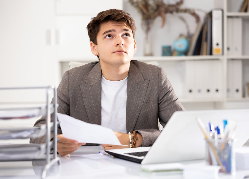 Male bookkeeper doing paperwork in workplace in office - checks accounting documents