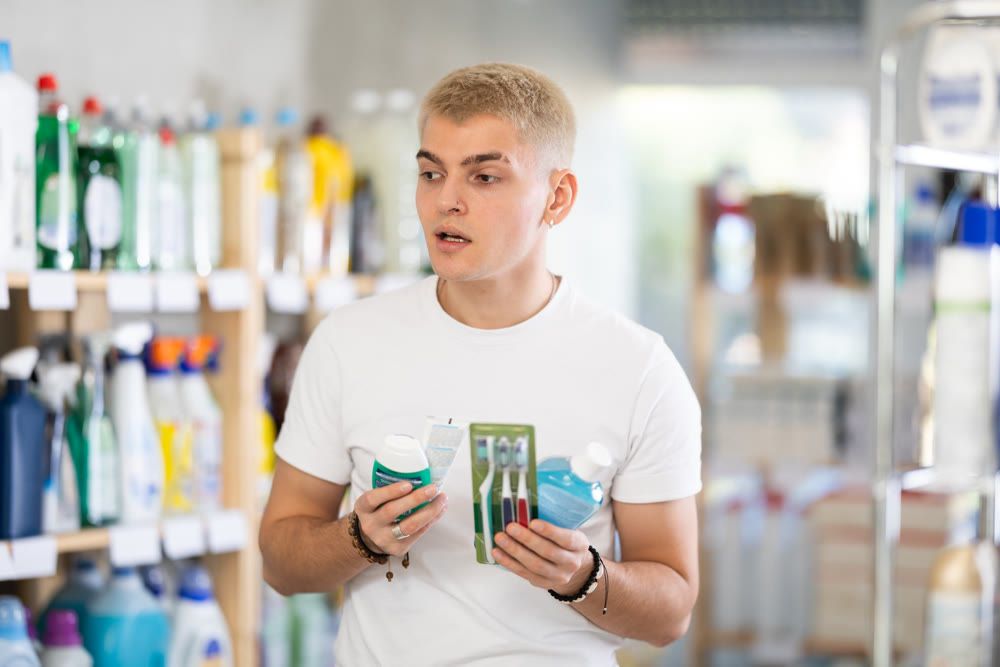 Male shopper chooses dental kit - toothbrush and toothpaste in shop