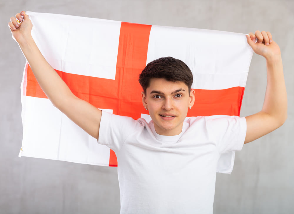 Portrait of positive young man holding England flag