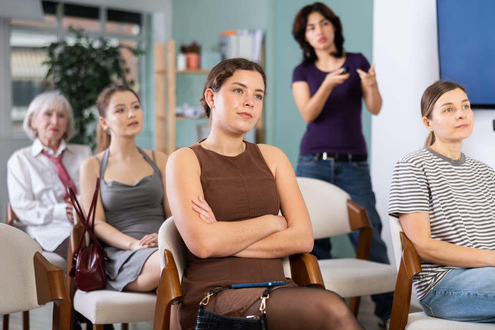 Focused female students sitting and watching presentation in conference hall at seminar, teacher in background
