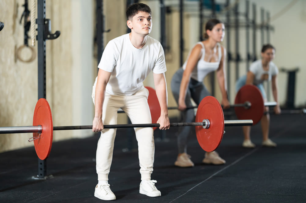 Young guy doing exercises with a barbell in gym