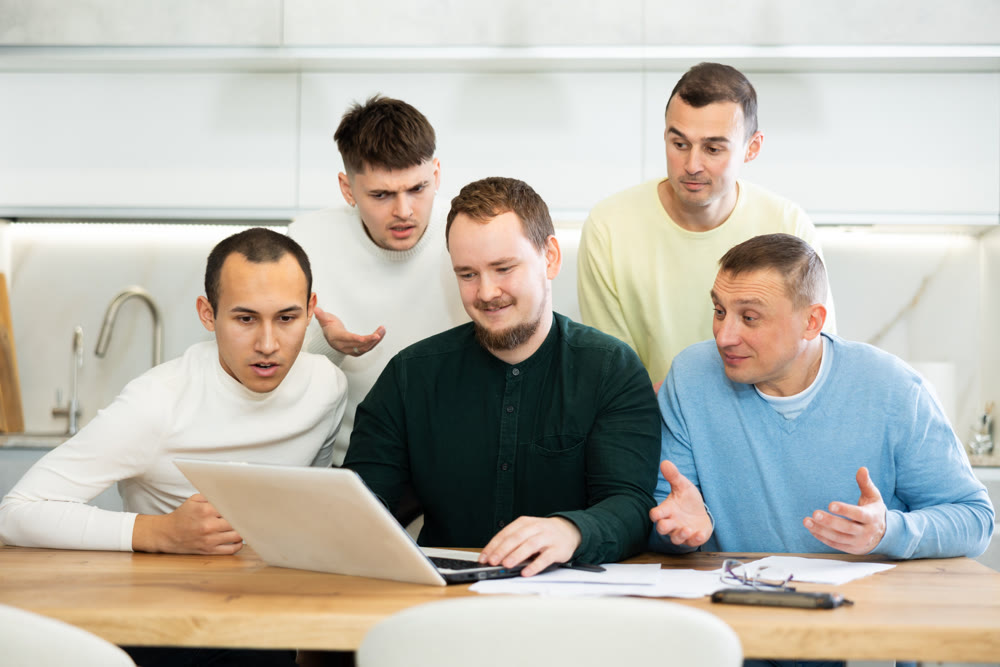 Group of men discussing with paperwork and laptop at home kitchen