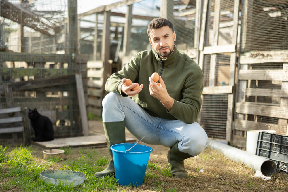 Positive man stands and holds in hands palms few fresh chicken eggs
