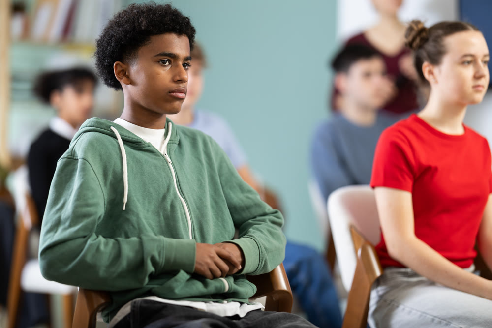 African American teen boy attendee group class and listen to lecturer.