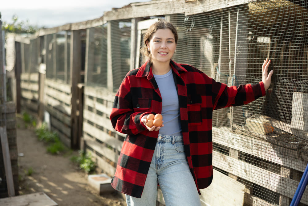 Young woman with chicken eggs in hen house
