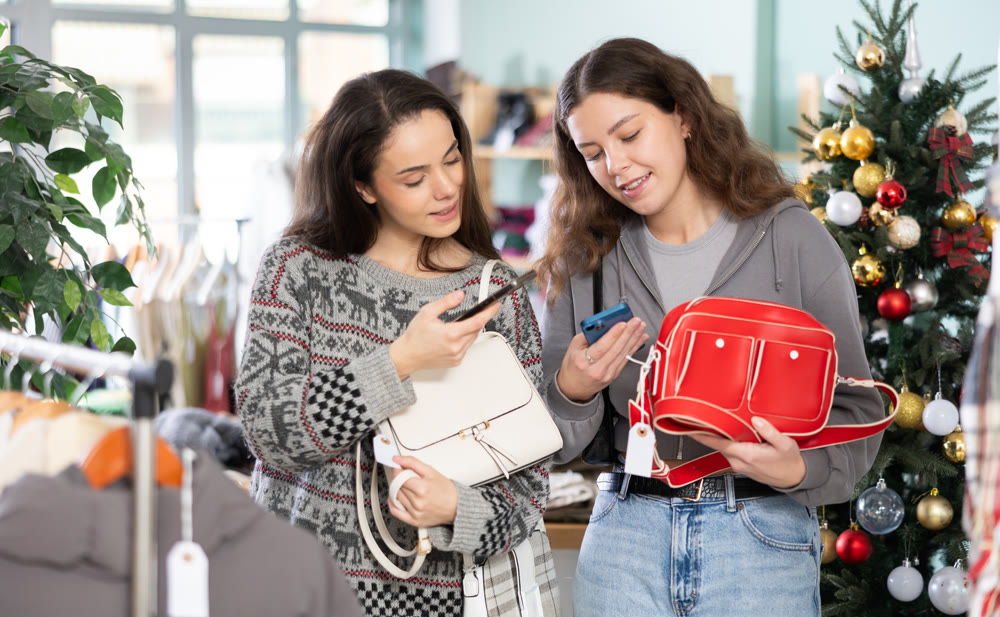 Two women with mobile phone in their hands scanning bag barcode