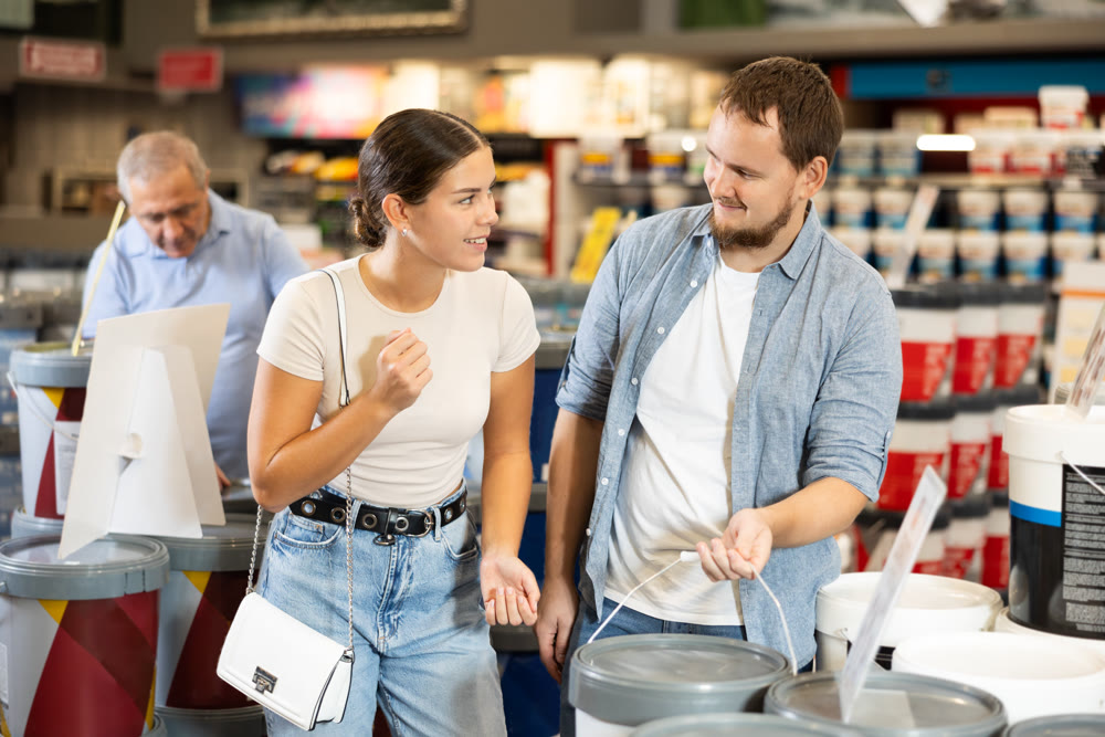 Couple man and woman choosing paint in store