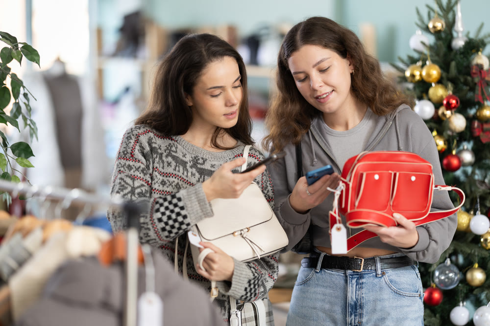 Two women with mobile phone in their hands scanning bag barcode