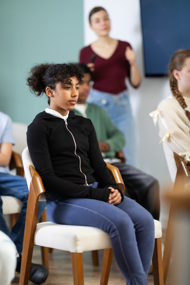 Afro American girl sitting in school classroom with classmates