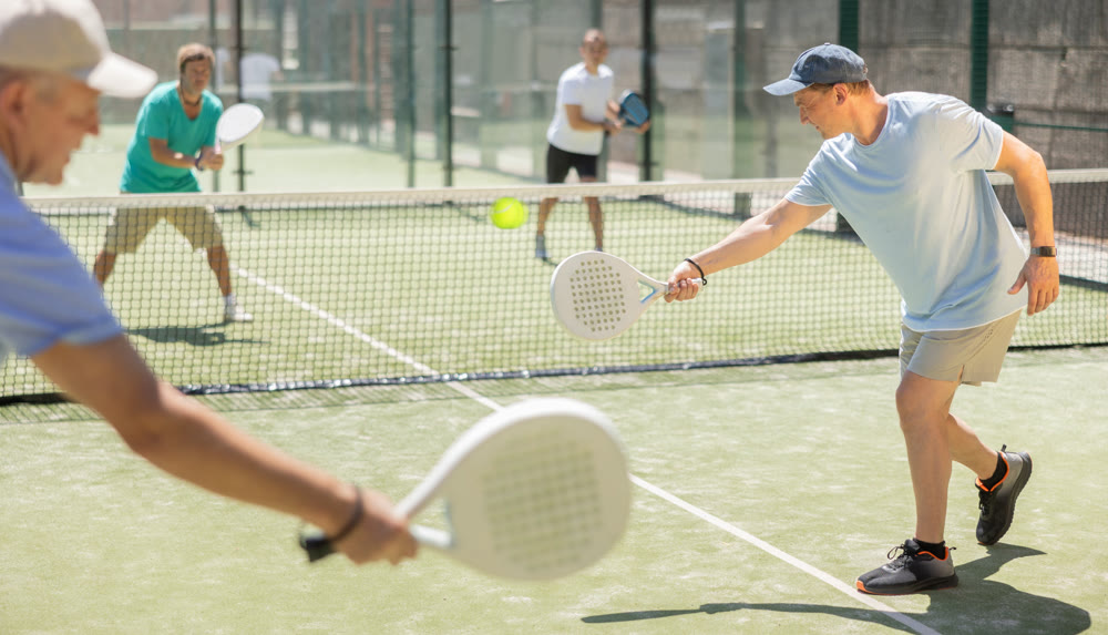 Adult and elderly men playing padel against two men
