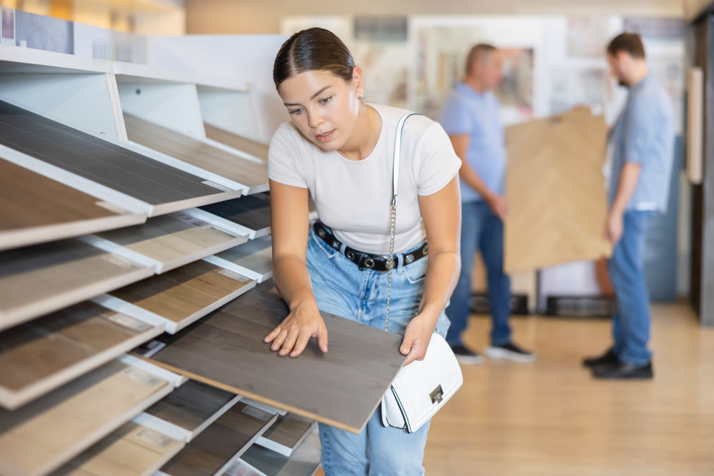 Woman buyer chooses sample of laminate flooring in hardware store