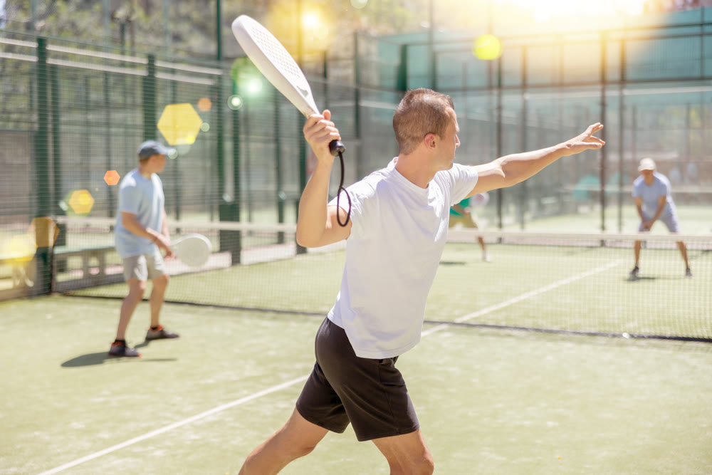 Active man with enthusiasm playing padel on tennis court