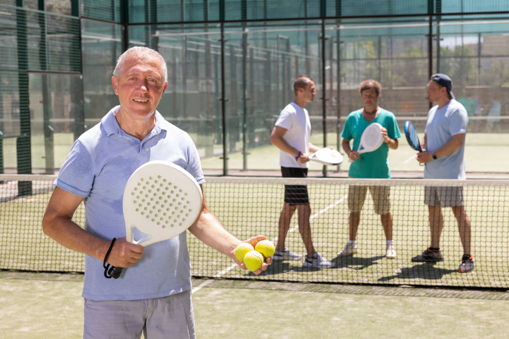 Portrait of satisfied elderly padel player after playing on tennis court