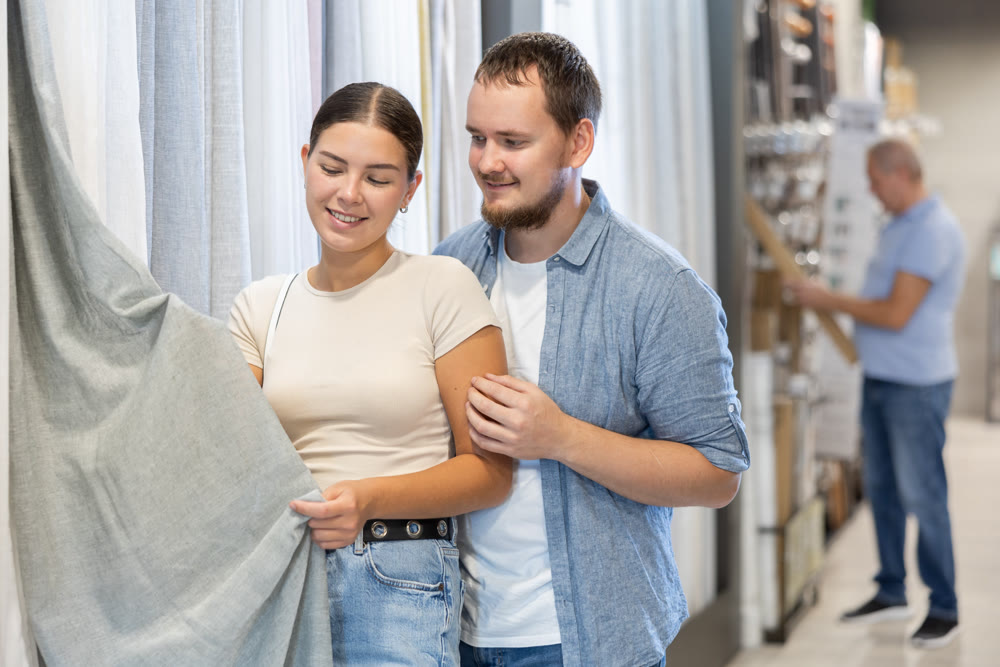 Couple man and woman choosing curtain in store