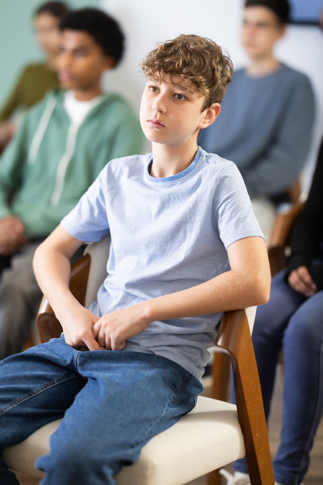 Boy sits next to his classmates and carefully looks at a lecture