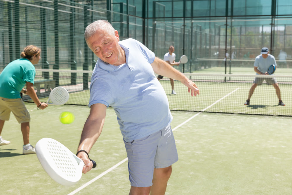 Adult and elderly men playing padel against two men