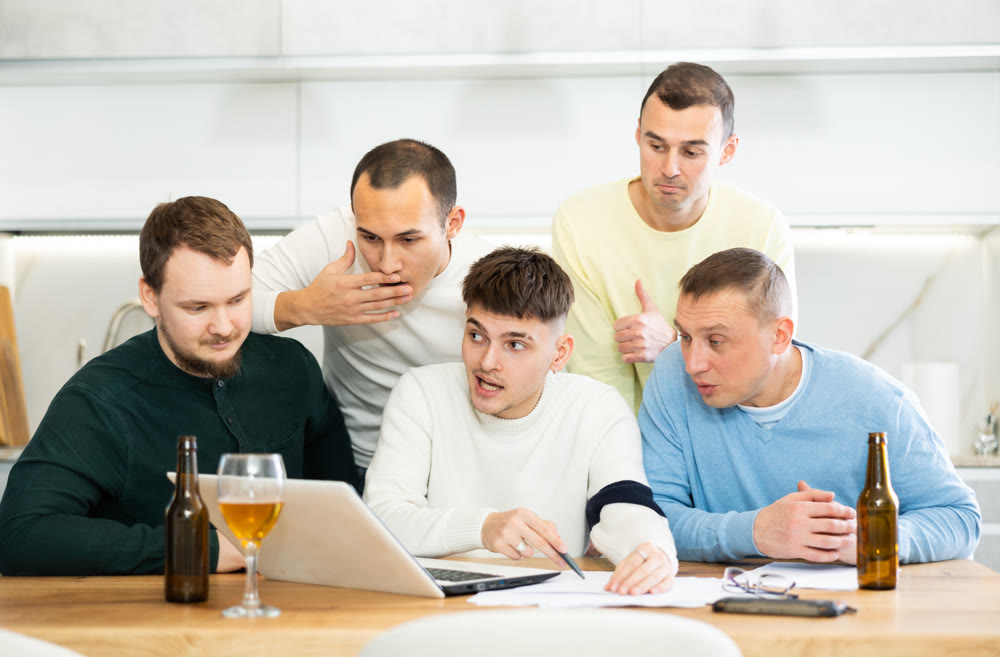 Group of football fans drinking beer and watching football match on laptop at home