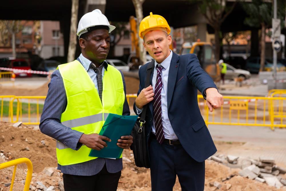 Engineer and architect are discussing options for laying a pipe on street
