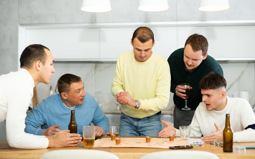 Male friends playing fun drinking board game at bachelor party