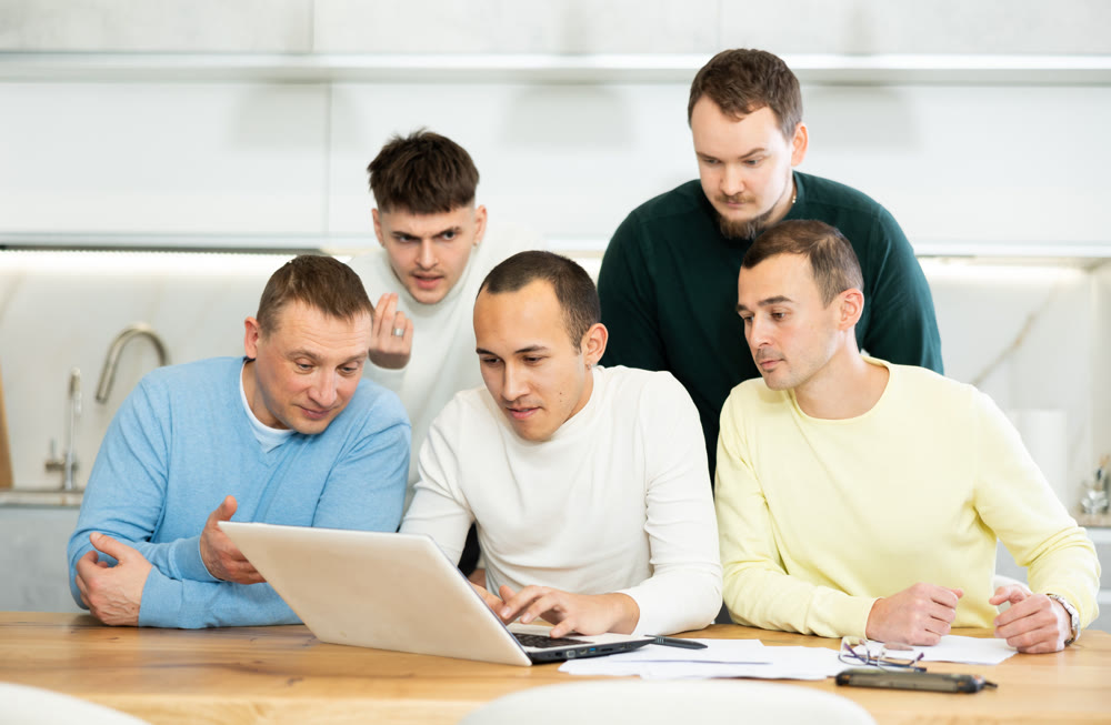 Interested men discussing content on laptop at home table