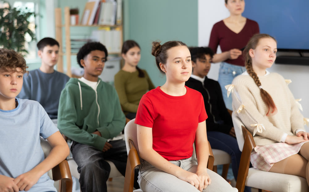 Teenage children sit in the classroom and look at the presentation