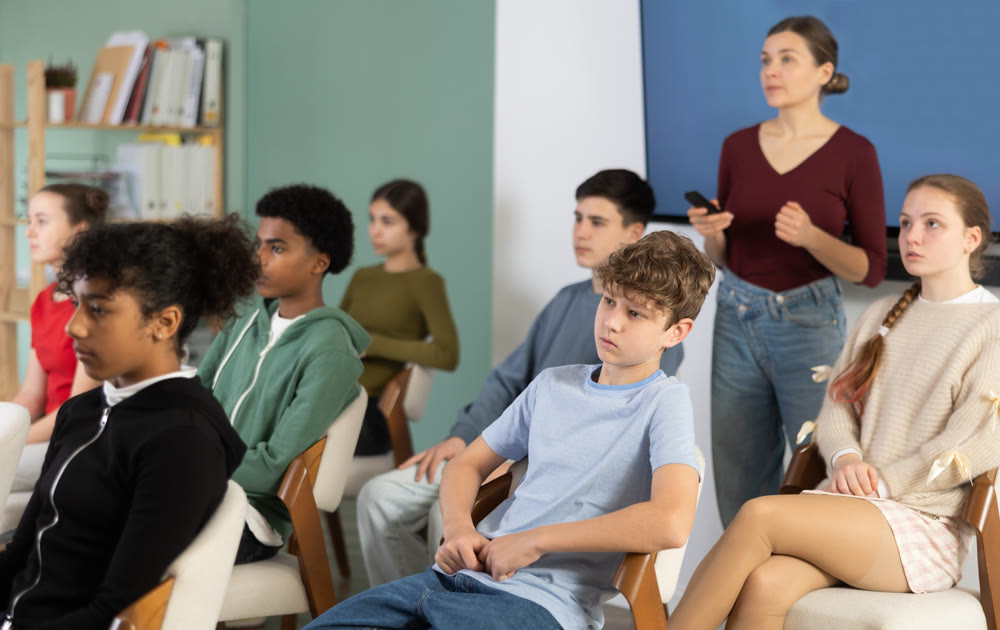 Teenage children sit in the classroom and look at the presentation