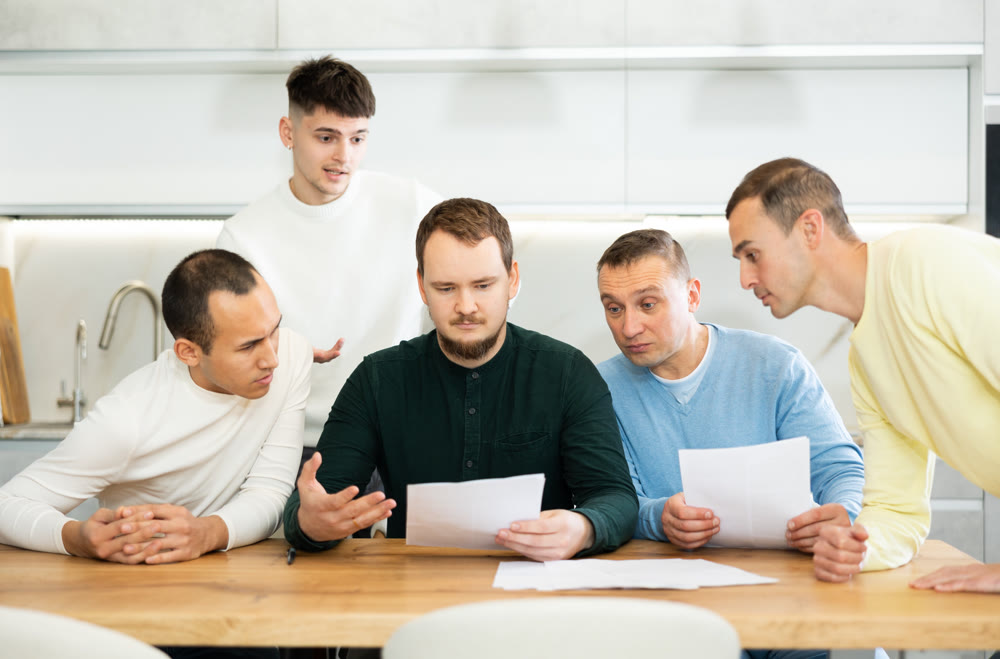 Group of men supporting troubled friend reading legal notice