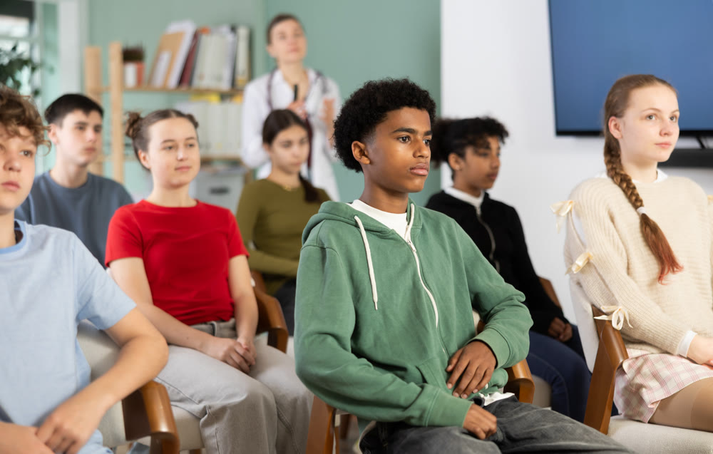 Schoolchildren carefully watch a lecture in the classroom against the background of a a doctor teacher