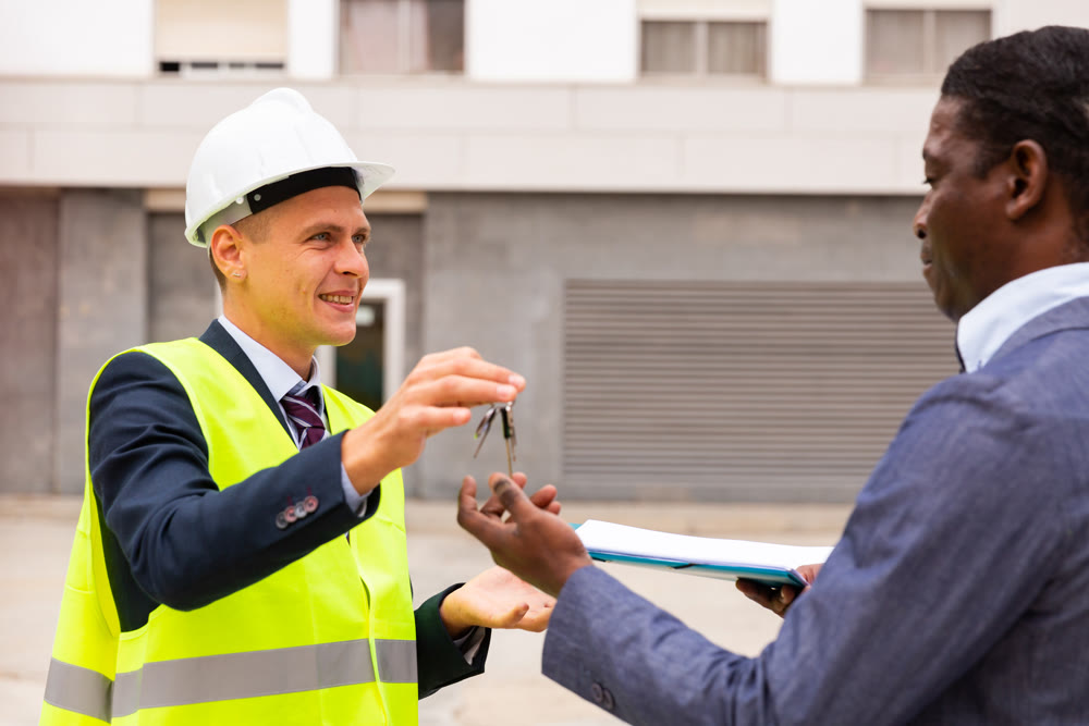 Young smiling contractor hands the keys to a man customer