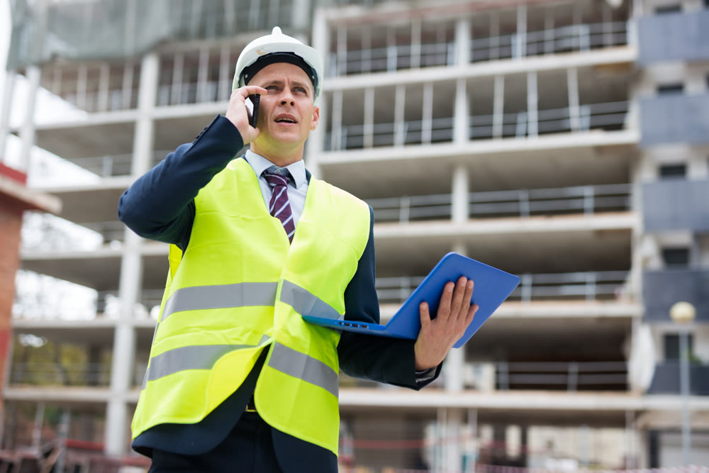 Young engineer, controlling the progress of work on a laptop, talking on a mobile phone