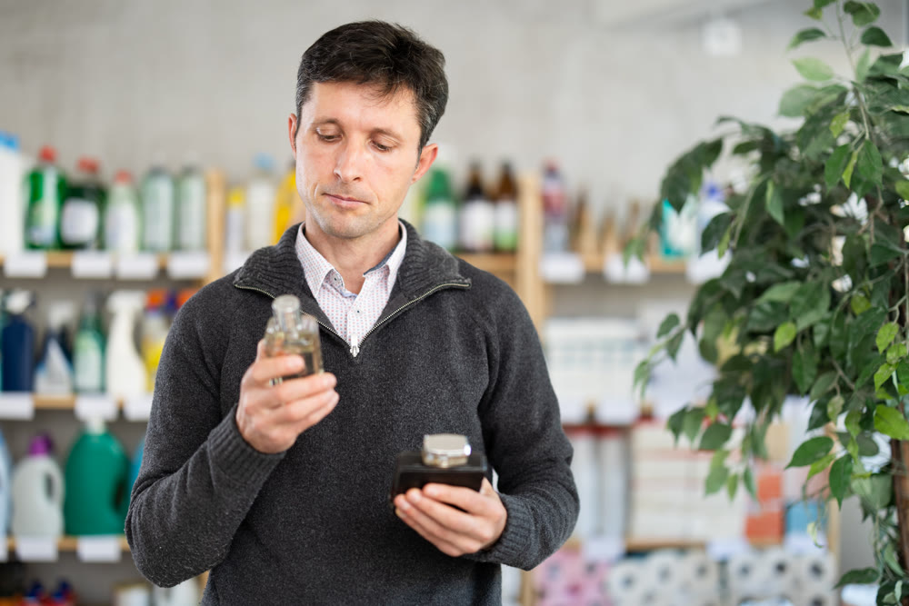 Male customer chooses perfume or aromatic incense in supermarket