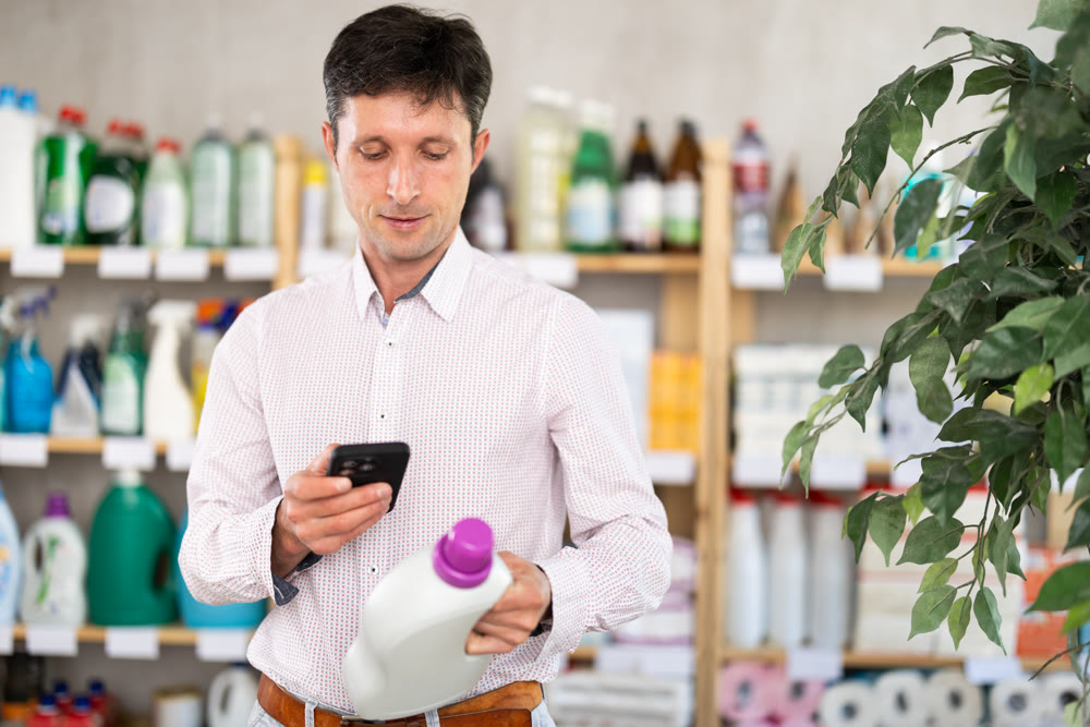Checking expiration date of detegrent - male shopper scans QR code on label of detegrent using smartphone