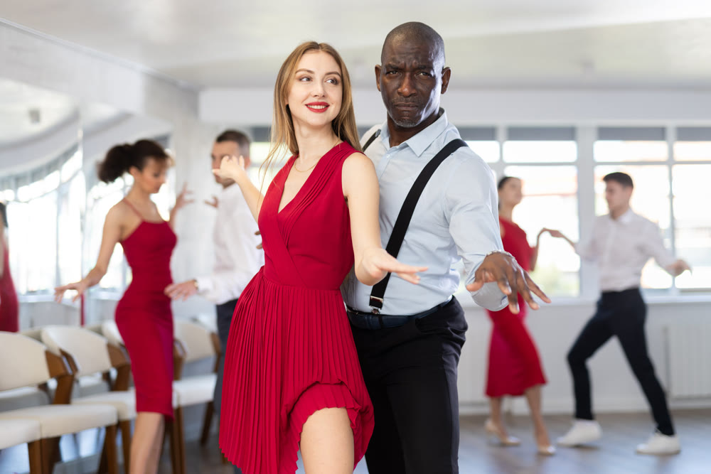 Woman dances incendiary boogie woogie with African man partner during choreography lesson