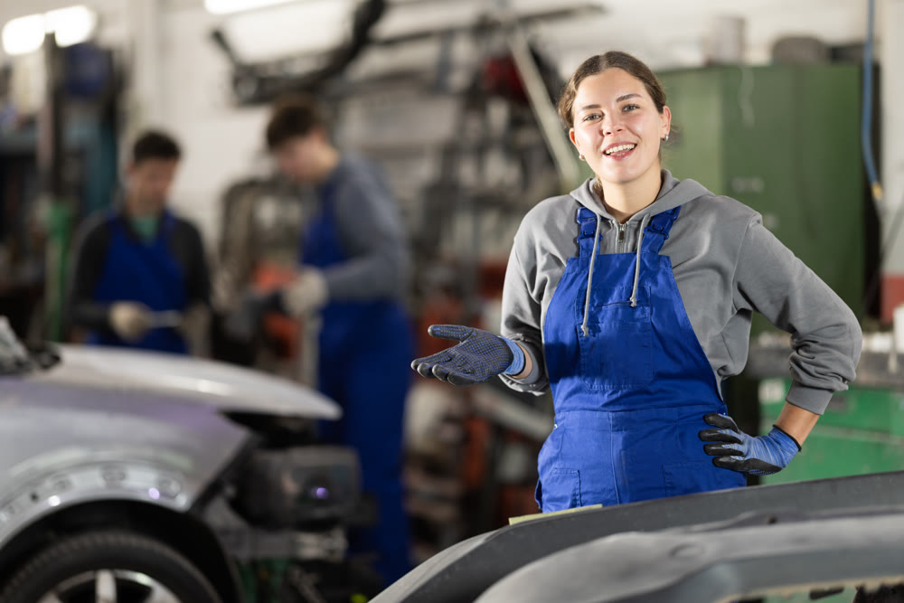 Portrait of a positive girl auto mechanic in the interior of car service