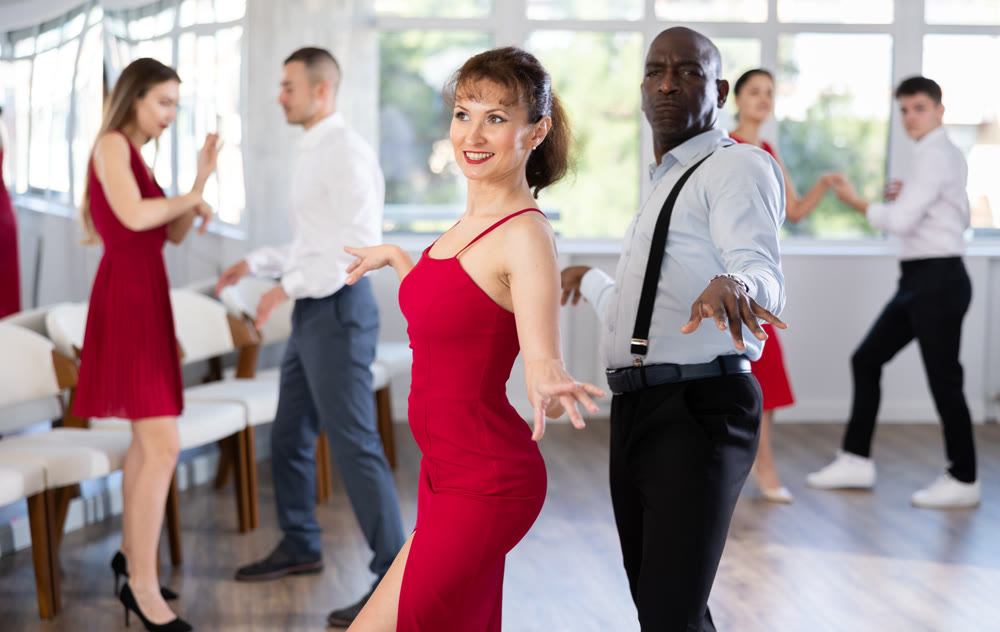 African American man and woman in red dancing twist in studio
