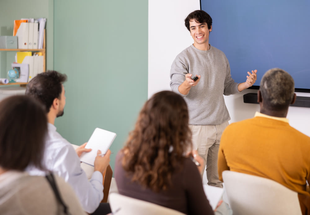 During lesson, young man teacher tells material and gives lecture