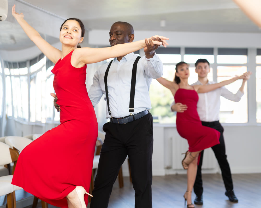 Black man enjoying impassioned merengue with woman in red in studio