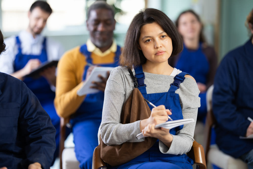 Young female worker listens and takes notes in lecture hall