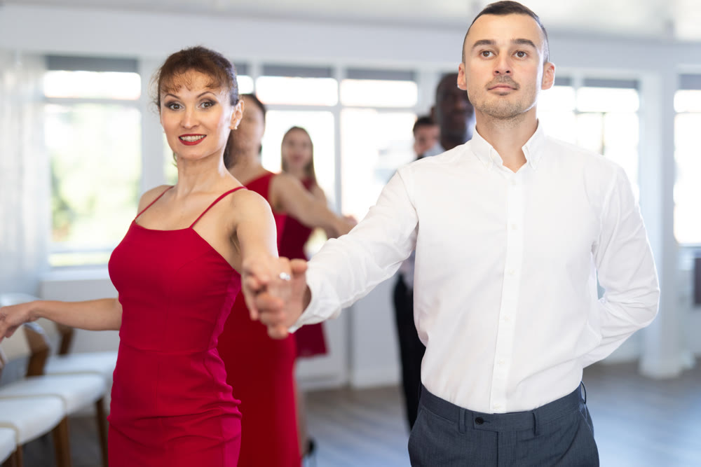 Woman in red enjoying slow foxtrot with partner in dance studio