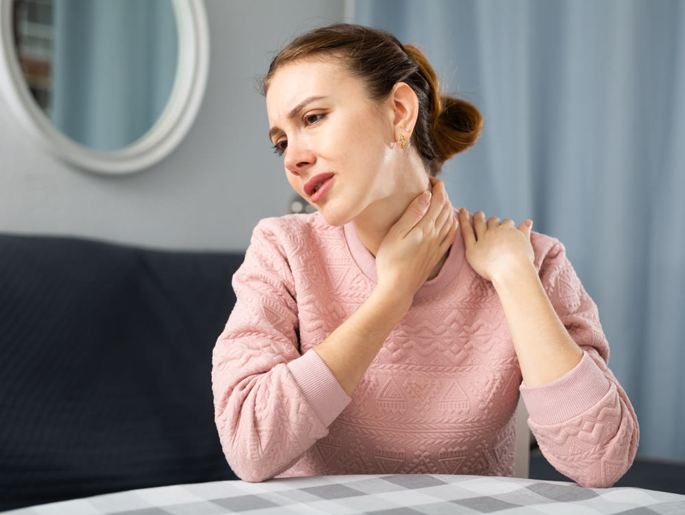 Woman suffering from pain in neck at home