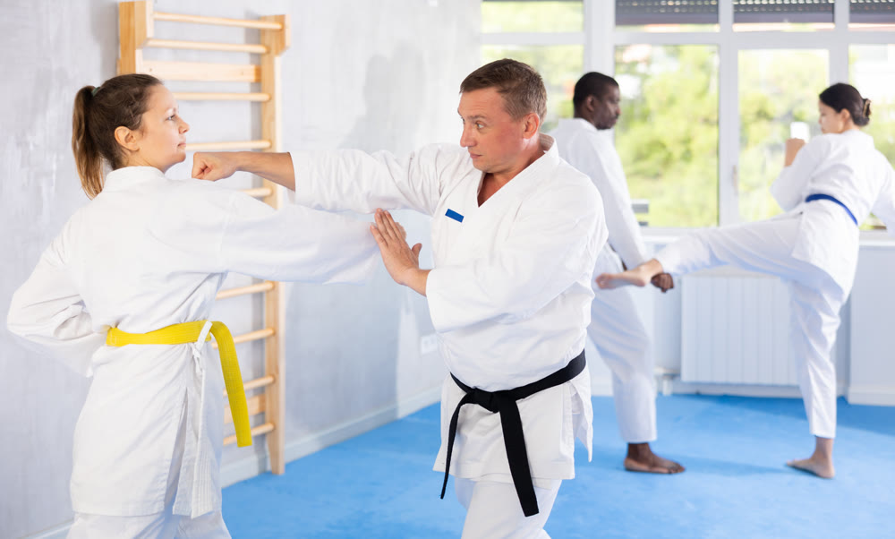 Woman and man in kimono sparring in gym during karate training