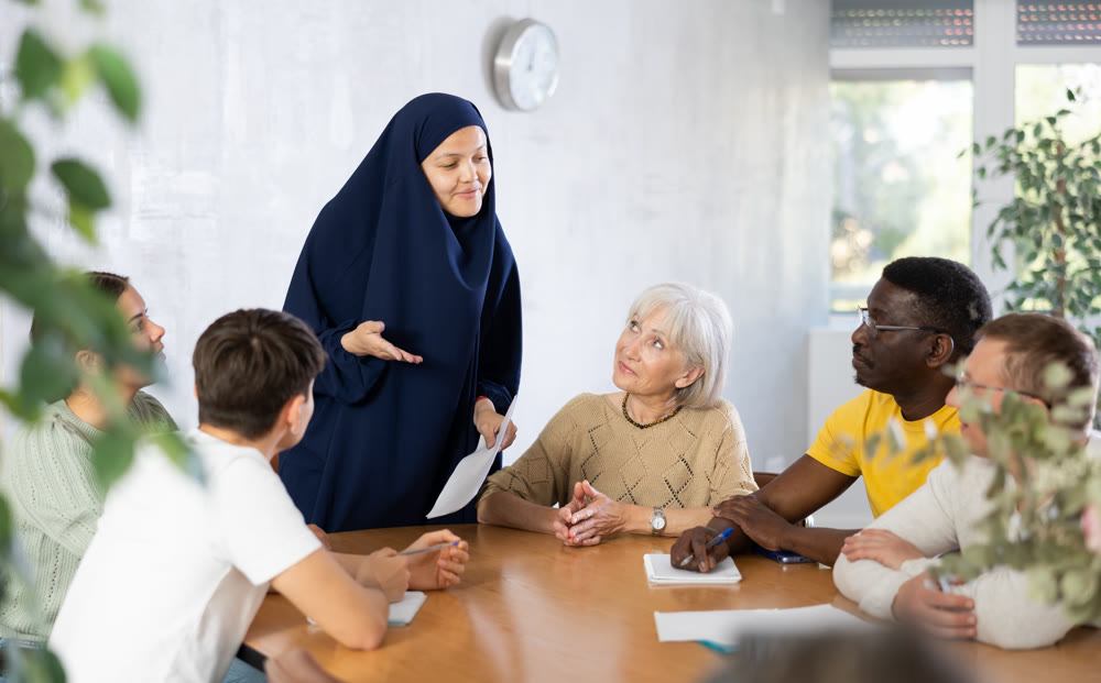 Asian woman in burqa tells an interesting story or conducts training for adult students of different nationalities