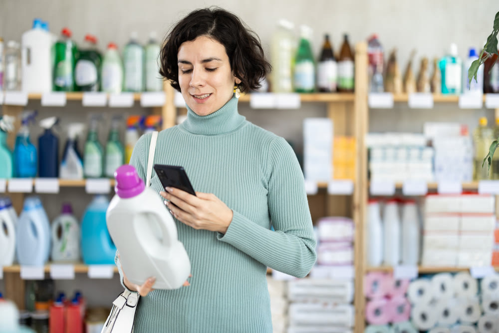 Middle-aged woman scanning QR-code on detergent at supermarket