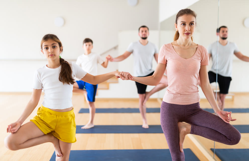 Family practicing yoga in pairs at studio
