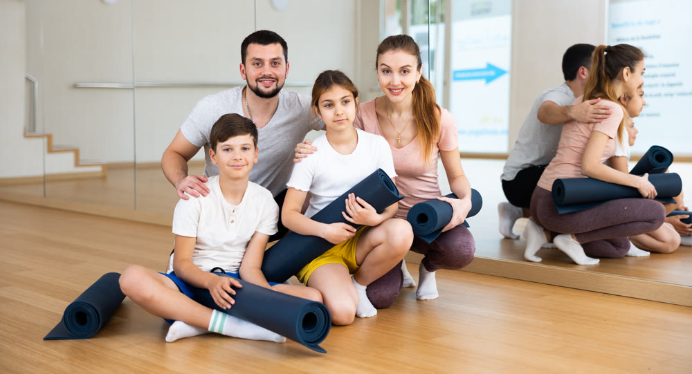 Happy family with rolled mats in gym